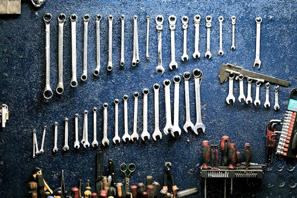 Organized wrenches and tools on blue workshop wall